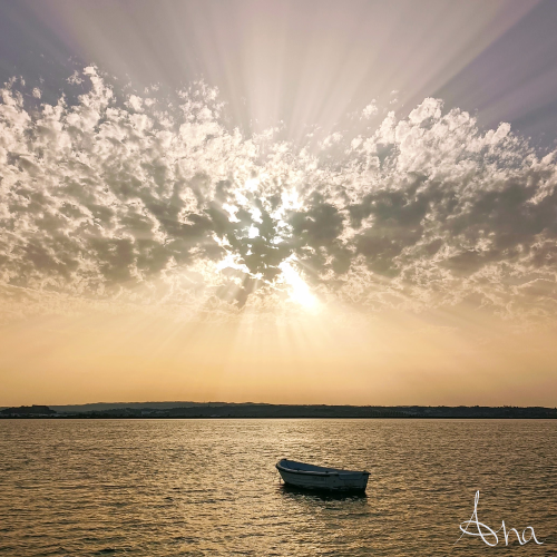 Small boat floating with the sunset in the background